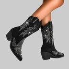 Black cowboy boots with silver embellishments on a gray background