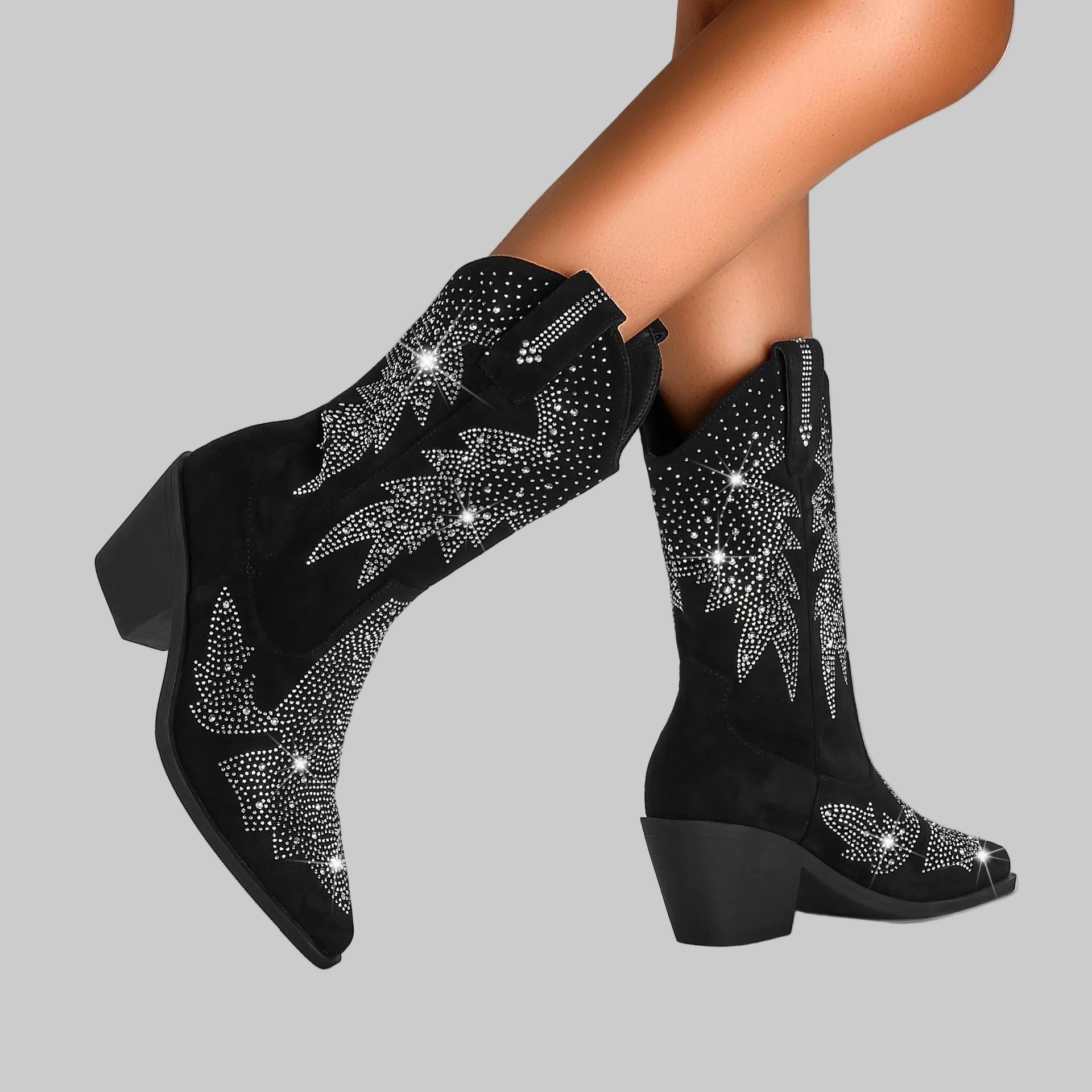 Black cowboy boots with silver embellishments on a gray background